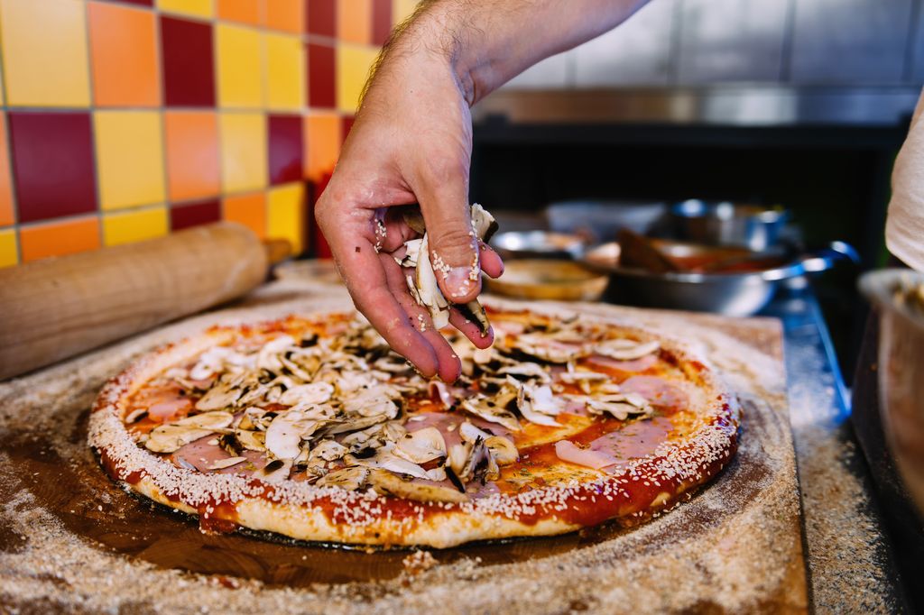 putting-mushrooms-on-pizza-in-pizza-restaurant-Y6VD2UN.jpg