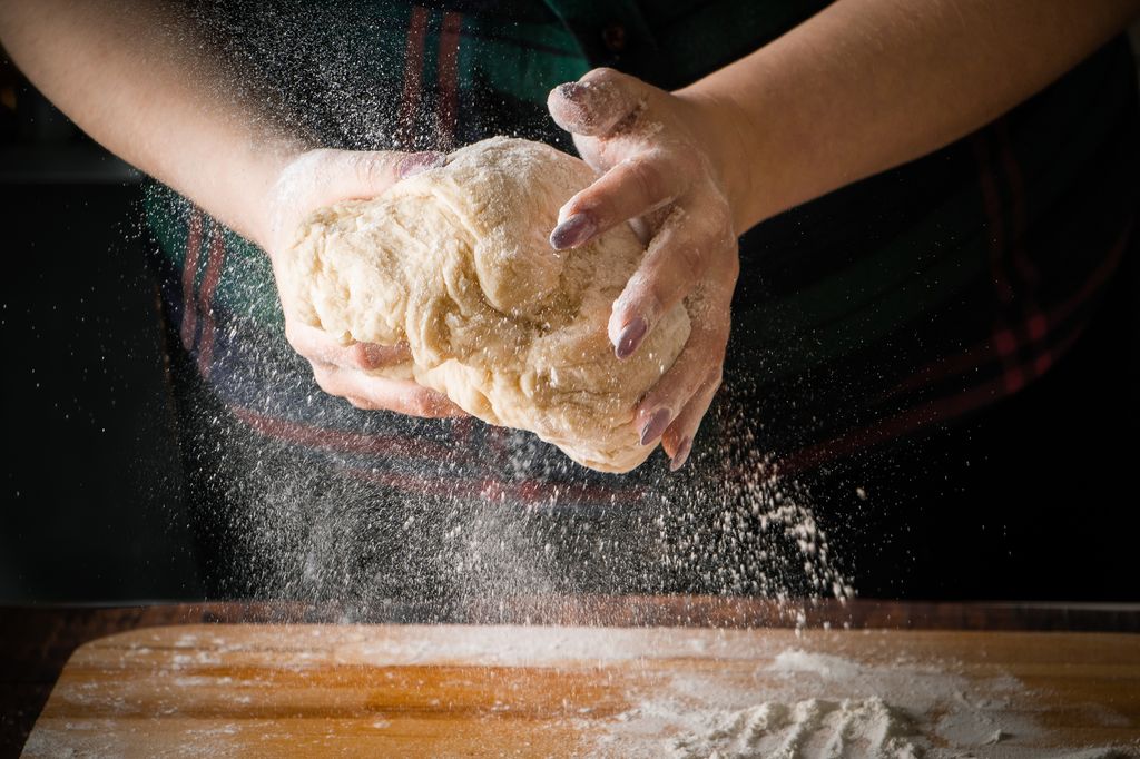woman-chef-kneads-pizza-dough-on-a-board-7PKQLUB.jpg